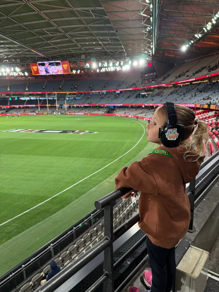Indi in her headphones, looking out over the ground at the footy