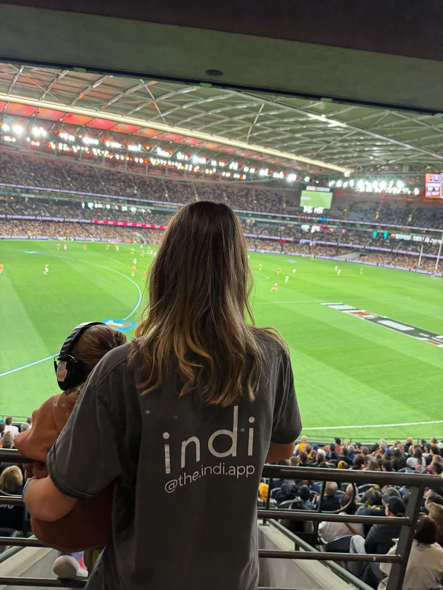 Allie, in an indi t-shirt, watching the footy from the stands